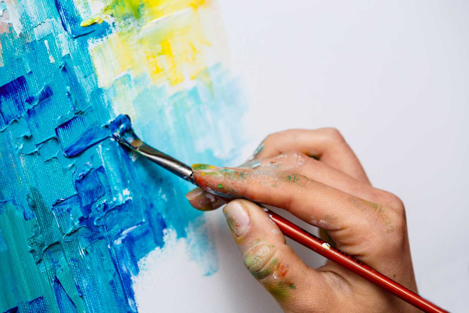 close up of girl drawing with oil paints on canvas.